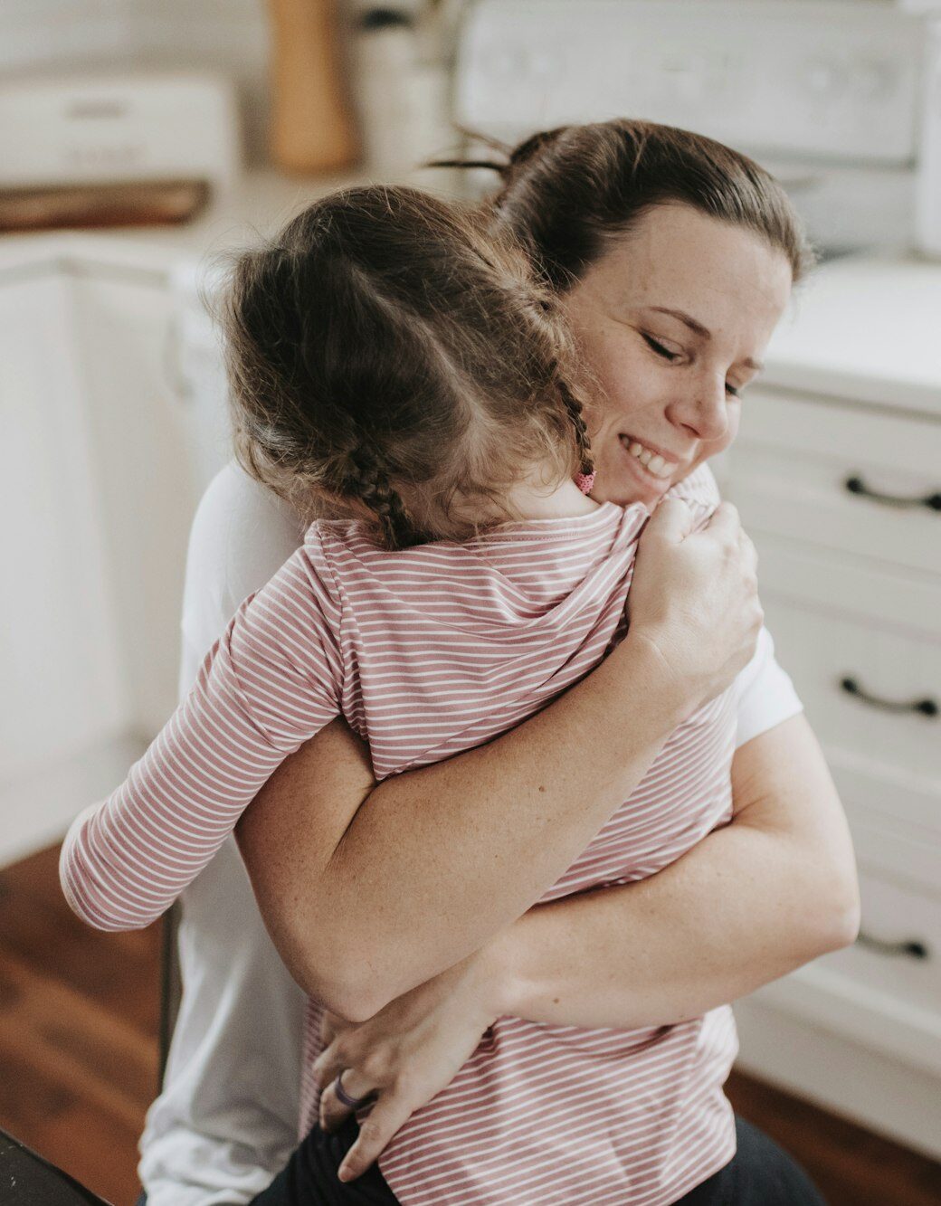 Mother hugging daughter in kitchen
